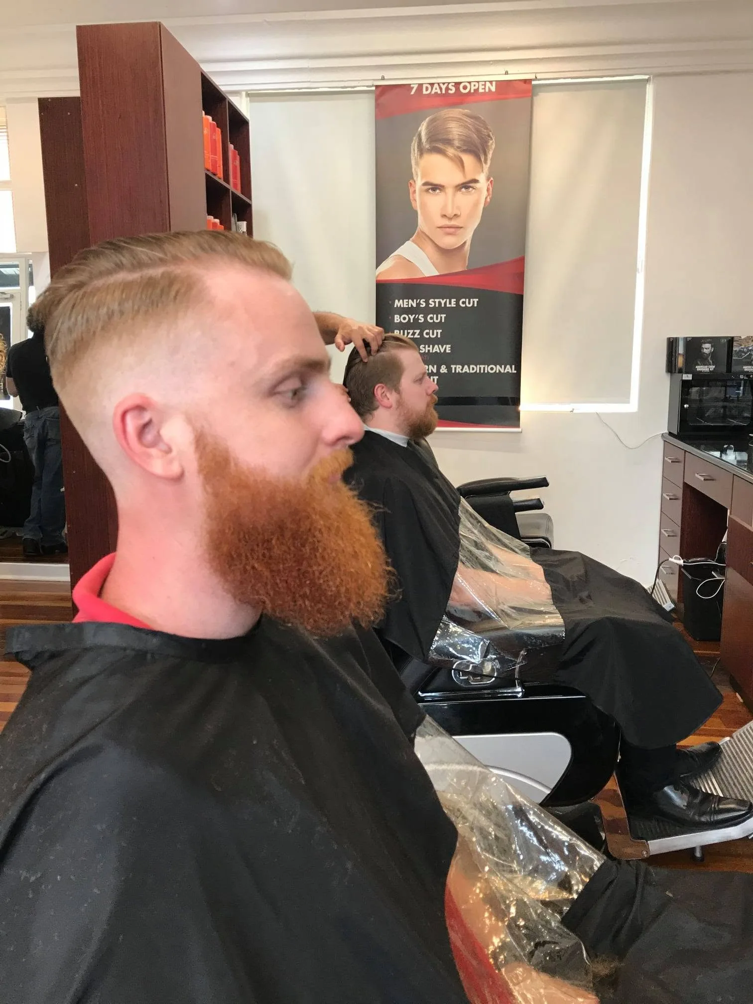Finished slicked-back cut, service banner in background