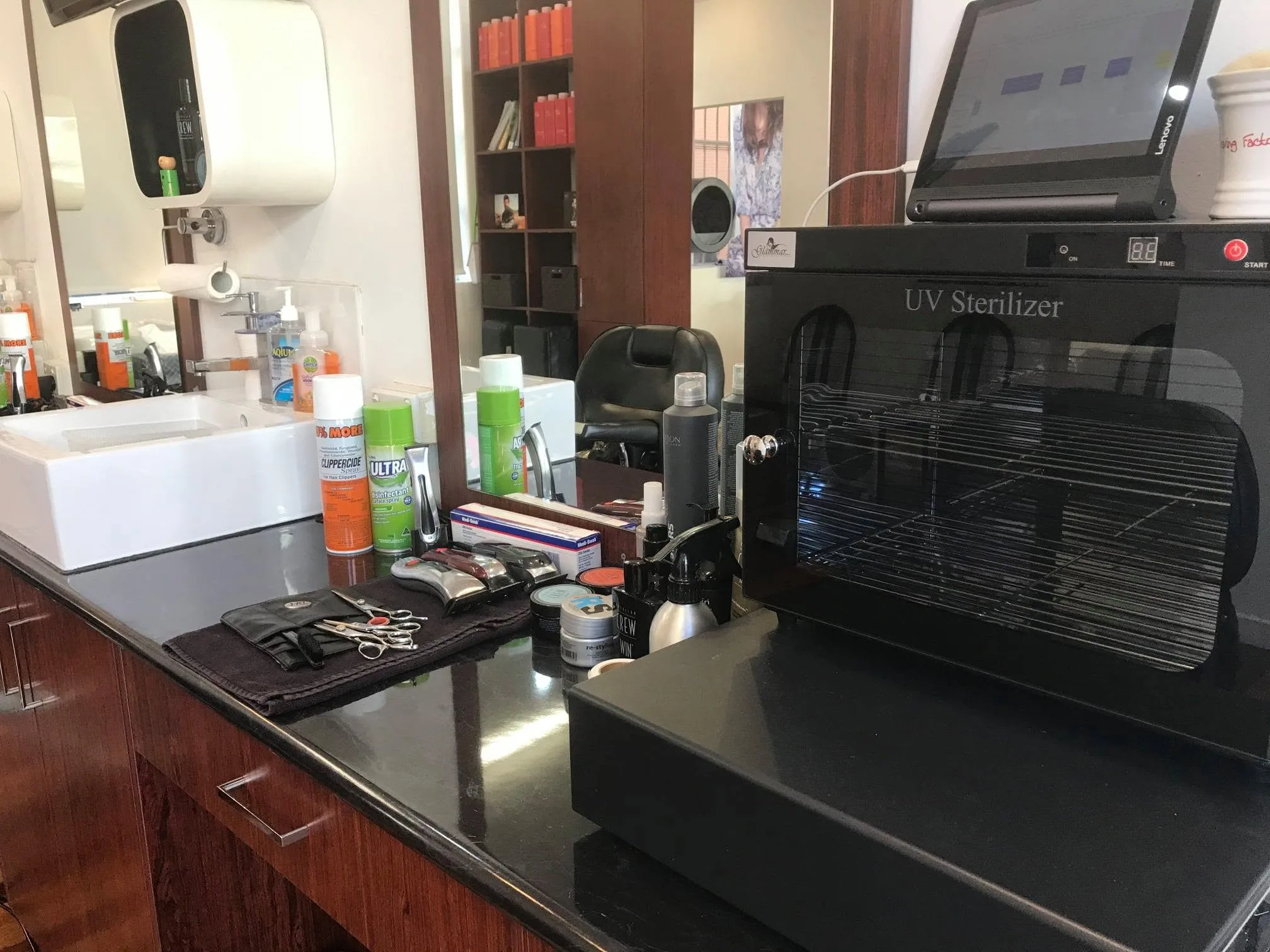 Barber station close-up — American Crew products, leather scissor roll, vessel sink